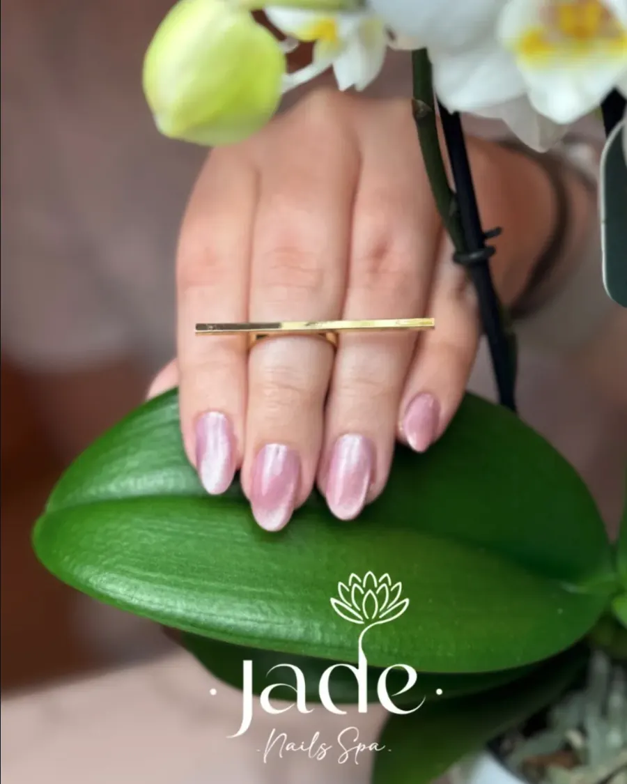 Mano con manicura sobre una orquídea y el logotipo de Jade